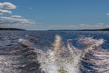 Motorboat stern wave in Finnish lake Päijänne on warm summer day