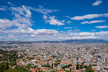 Fototapeta na wymiar Athens city against blue cloudy sky in a spring day. Aerial view from Acropolis hill. Attica, Greece,