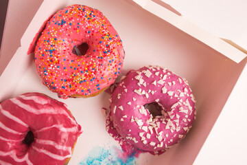 Multi-colored donuts in a white box close-up.