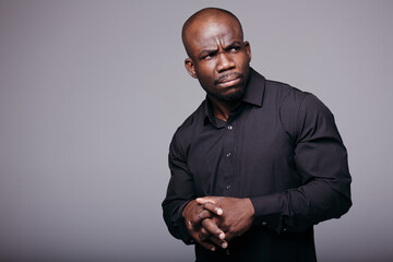 African office worker in a black shirt put a hand on his chest, and unhappy because of problems at work.