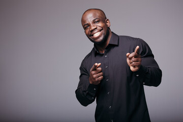 African male looking at the camera and shows an approving gesture with his fingers. Black man in a shirt happy.