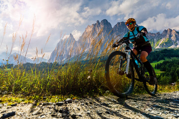 Fototapeta premium Cycling outdoor adventure in Dolomites. Cycling woman in Dolomites landscape. Woman cycling MTB enduro trail track. Outdoor sport activity.