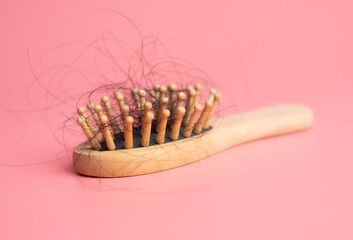 Black hair loss problem with hairbrush on pink background