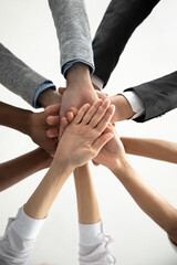 Close up bottom view vertical photo diverse business people stacking hands in pile at corporate...