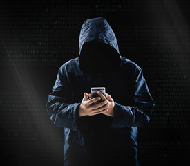 Internet crime concept,Hooded hacker using smartphone in dark room