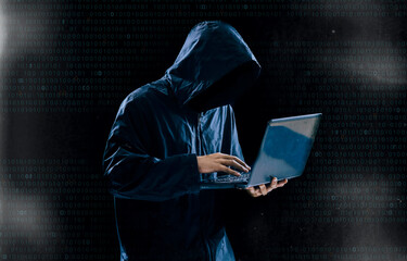 Internet crime concept,Hooded hacker using laptop in dark room