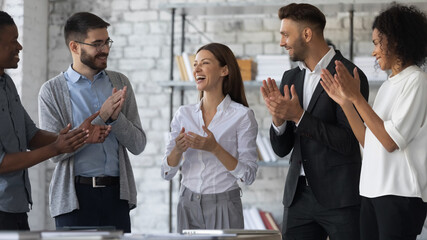 Friendly diverse employees congratulating businesswoman with business achievement, great work results or job promotion, business people applauding and cheering, standing in modern office - obrazy, fototapety, plakaty