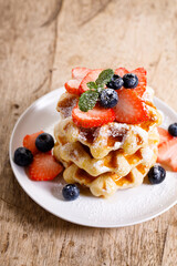 belgian waffles with fresh blueberries, strawberries and sugar.
