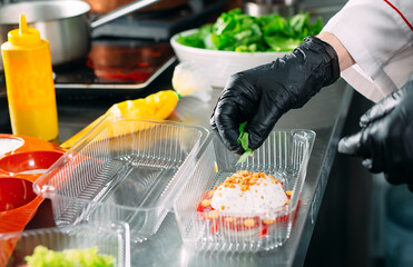 Food delivery in the restaurant. The chef prepares food in the restaurant and packs it in...