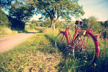 Naklejka premium Vieux vélo rouge sur un chemin de campagne au printemps.