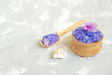 Fototapeta na wymiar Wooden spoon and bowl with purple sea salt on grey background.Background for advertising salty.