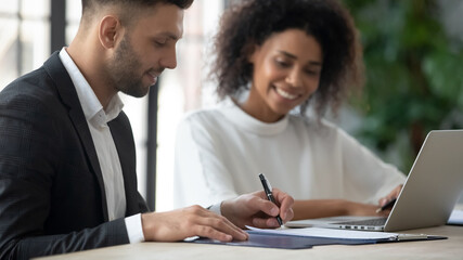 Satisfied customer signing contract at meeting, making deal with African American businesswoman,...