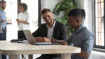 Satisfied African American customer signing contract at meeting with manager, making great deal,...