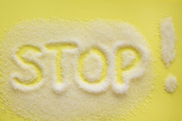 Stop, inscription on sugar, an exclamation mark. Diet and weight loss, refusal of sweet. Diabetes problems, harm from eating, dependence on flavoring. Many small grains on a yellow background.