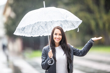 Smiling pretty girls with an umbrella checks with her hand, whether it is still raining