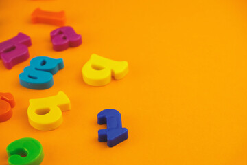 Plastic colourful alphabet letters on the orange background.