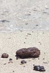 Volcanic Pebbles on a sandy beach with the gentle calm waves lapping behind, Lobos Island Corralejo, Fuerteventura. Space for copy text