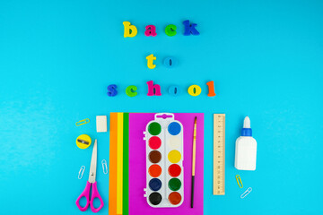 Back to school concept. Flat lay stationery set, top view of scissors, watercolour paintings, brush, paper and glue.
