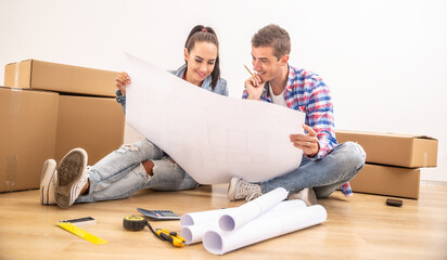Happy couple moved into a new house  discussing the interior design over blueprints