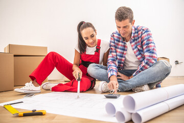 Young couple in casual clothes and an overall plan the apartment decoration over paper plans