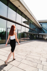 Naklejka premium Young business woman walks along modern building