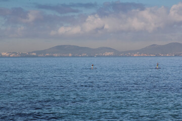 Two people are sailing in the sea on a surfboard. Mallorca, Spain. Balearic Islands
