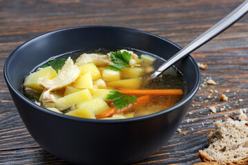 Chicken noodle soup and herbs in a plate on wooden boards, shallow depth of field, selective focus. The concept of healthy home nutrition.
