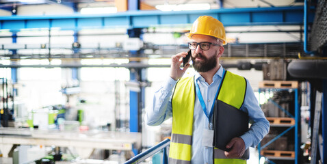 Technician or engineer with protective mask and telephone working in industrial factory.