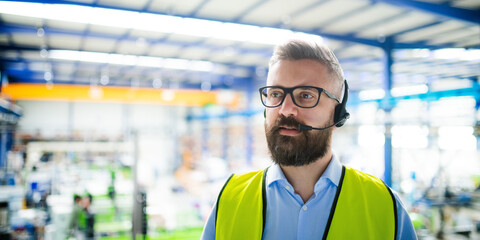 Technician or engineer with protective mask and headset working in industrial factory.