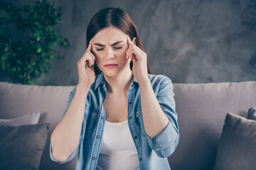 Portrait of frustrated girl sit divan have terrible migraine high blood pressure touch finger head...