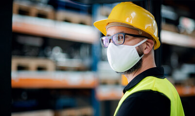 Technician or engineer with protective mask and helmet standing in industrial factory.