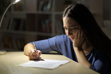 Worried sad woman signs contract at night at home