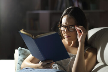 Woman with eyesight problem reads book at night