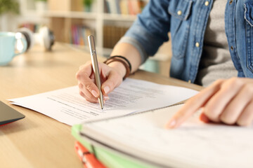 Student girl hand doing exam checking notebook