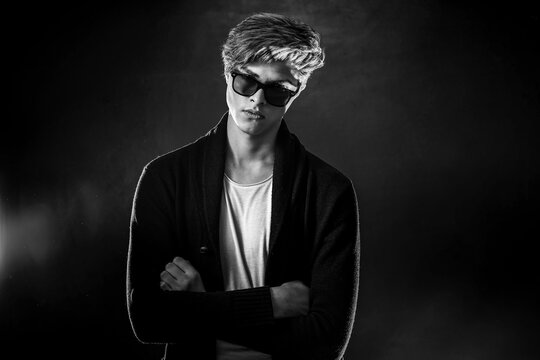 Trendy young man with cool hairstyle wearing black jacket with sunglasses.  High Fashion male model posing on black background. Art design concept  Stock Photo | Adobe Stock
