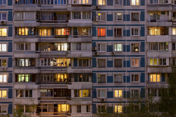 Fototapeta na wymiar Facade of large multi-storey block residential buildinf with many bright lighting windows in apartments and balconiesю Evening view. Moscow Russia