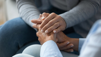 Adult daughter comforting old mom strokes holds her hand close up view. Strong connection confidential conversation, empathy and mercy, support in hard life period, be near sharing heart pain concept