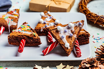 Christmas tree brownies with candy cane and icing, gray background. Christmas food concept.