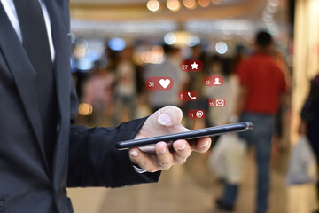 Close up of businessman using mobile smartphone with social media icons over blurred airport station background. Business, technology or social network concept.