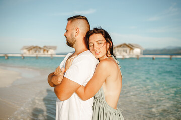 Couple on the beach at tropical resort. Travel honeymoon concept. Happy loving couple hug each other on white sand beach on Maldives