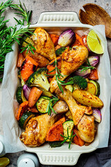 Roasted chicken legs with vegetables in the oven dish, top view. Baked chicken with sweet potato, zucchini and broccoli.