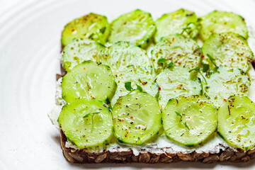 Cucumber and cream cheese toast on white plate, top view. Healthy vegetarian diet concept.