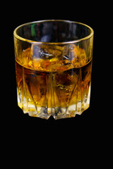 Glass of whiskey with ice on a black background