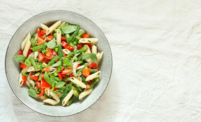 salad in a bowl of pasta, asparagus, bean pods, tomatoes, green peas, basil. top view, copy space