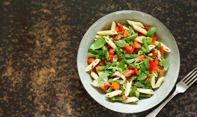salad in a bowl of pasta, asparagus, bean pods, tomatoes, green peas, basil. top view, copy space