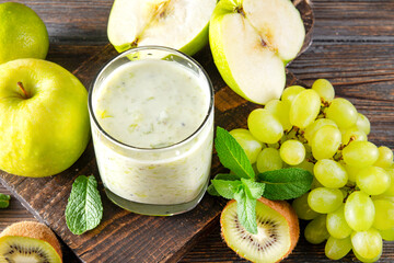 glass of  yogurt with fresh kiwi, green grapes, Apple and mint on a wooden