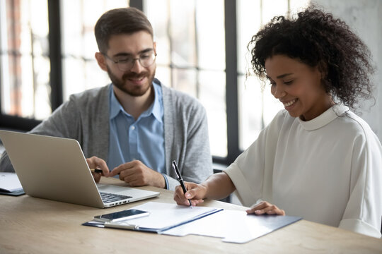 Smiling African American woman signing contract at meeting with manager, sitting at table, satisfied customer making great deal, successful candidate putting signature on job agreement