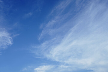Light and transparent clouds against the blue evening sky with the moon
