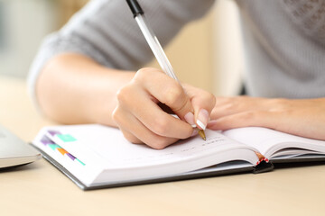 Woman hands writing notes on agenda on a desk