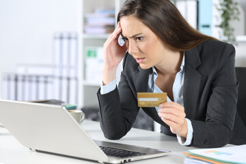Worried executive paying with card on laptop at office